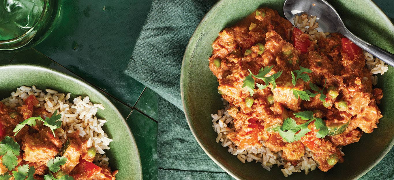 Two green ceramic bowls of brown rice topped with Carleigh Brodug’s Any Vegetable Curry and a garnish of fresh cilantro