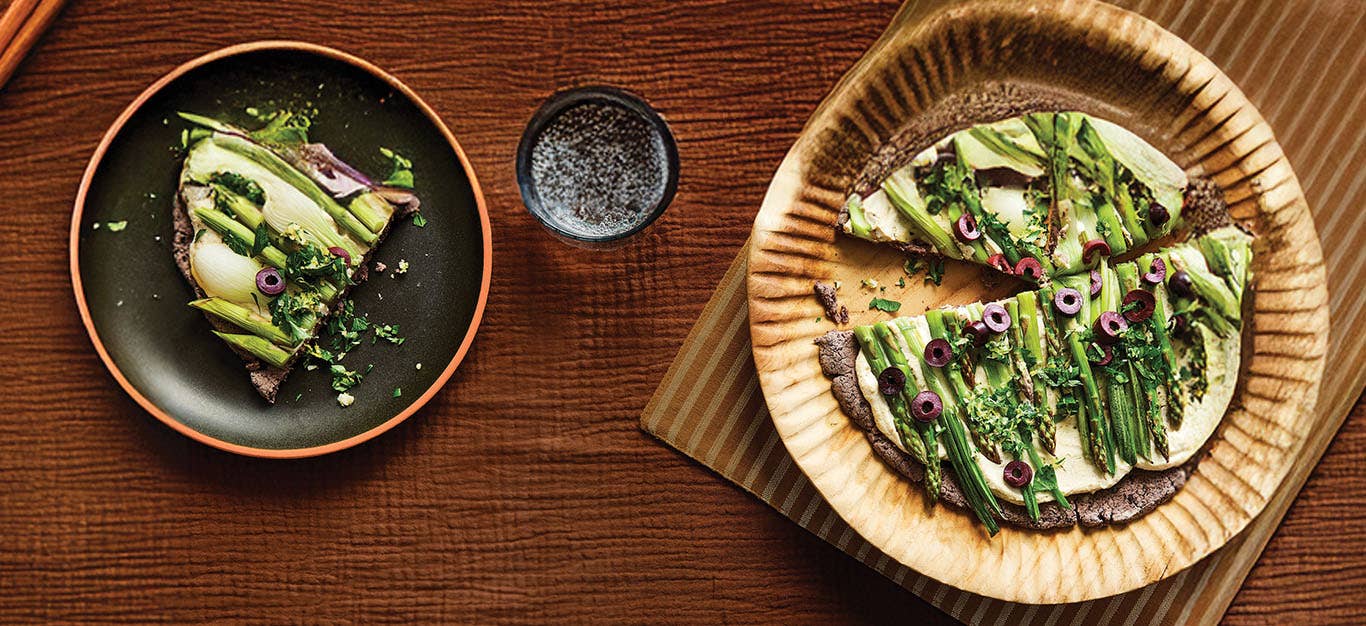 Spring Onion and Asparagus Tarts with Black Bean Crust on a dinner-sized plate, with one slice removed on a smaller plate