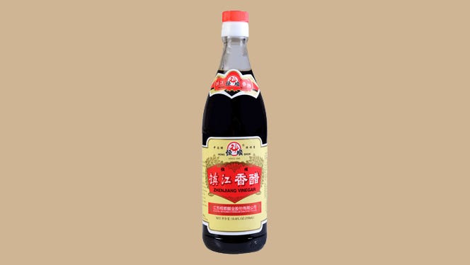 black-vinegar A bottle of Chinese black vinegar isolated on a tan background