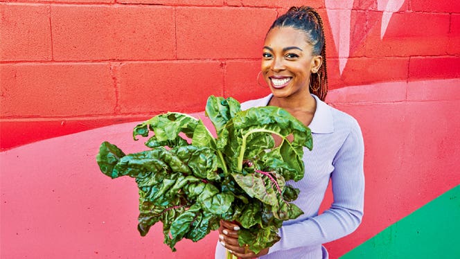 Cookbook-author-Jenne-Claiborne-holds-a-bushel-of-collard-greens-and-smiles-while-standing-in-front-of-a-bright-pink-and-red-wall-outside Cookbook author Jenne Claiborne holds a bushel of collard greens and smiles while standing in front of a bright pink and red wall outside.jpg
