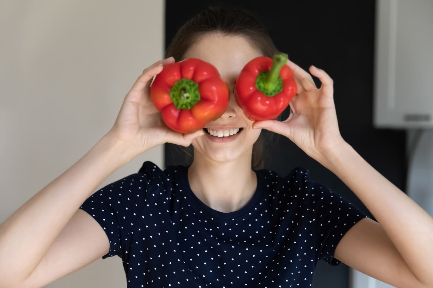 lady-with-pepper-eyes A young woman holds up two bell peppers to her eyes and smiles